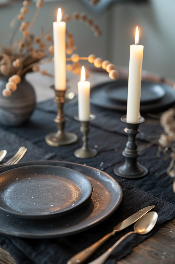 How to Create a Dark Farmhouse Dining Room That Feels Like a Gothic Country Estate Close-up dark farmhouse tablescape with matte black ceramics, aged brass flatware, and white taper candles